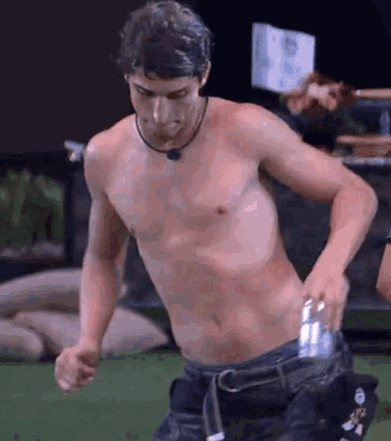 a shirtless man is holding a can in his pocket .