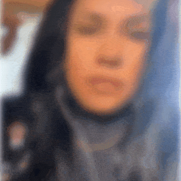 a blurry picture of a woman wearing a scarf with her eyes closed