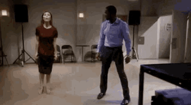 a man and a woman are dancing in a room with chairs .