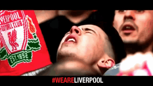 a man wearing a liverpool football club shirt is laying on the ground