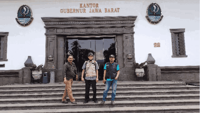 three men stand in front of the kantor gubernur jawa barat