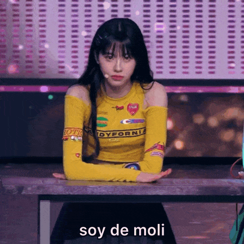 a girl in a yellow shirt is sitting at a table with the words soy de moli written on it