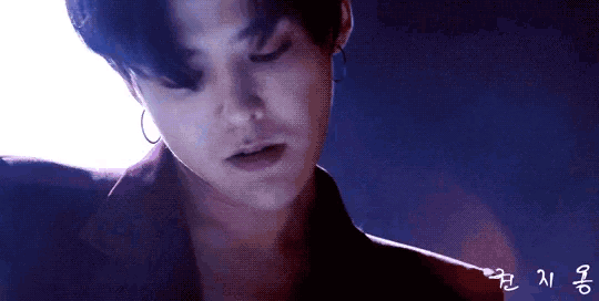 a close up of a man 's face in a dark room with a purple background .