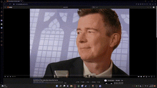 a computer screen shows a man in a suit and tie making a funny face .