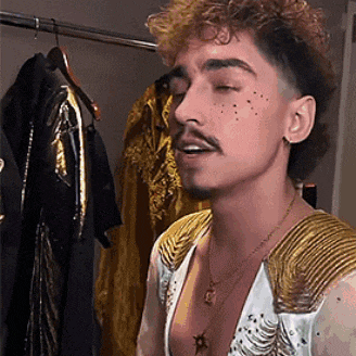 a man with a beard and mustache is wearing a white and gold outfit