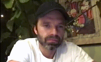 a man with a beard wearing a white shirt and a black hat