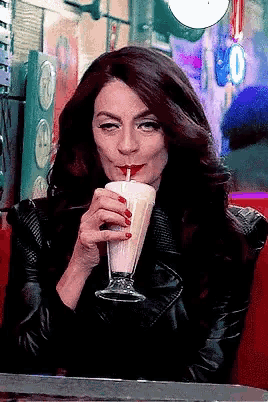 a woman is drinking a milkshake with a straw