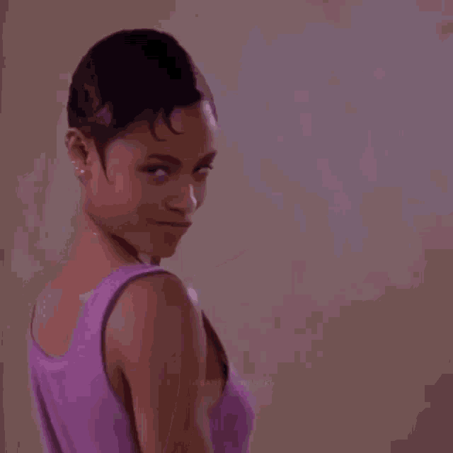 a woman in a purple tank top is making a funny face with her finger .