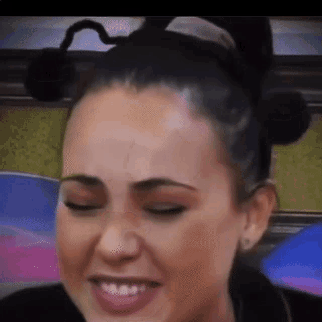 a close up of a woman 's face with her eyes closed wearing a mickey mouse headband .