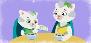 two cats are sitting at a table with a carton of milk and a bowl of cereal