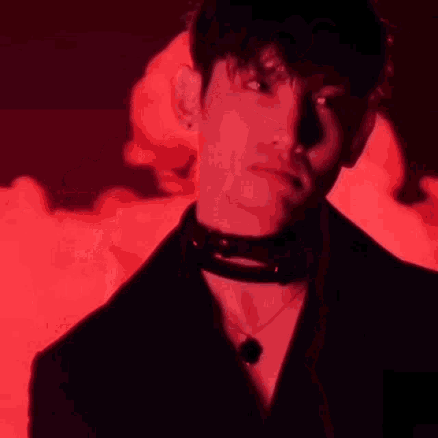 a man in a suit is standing in front of a red smoke .