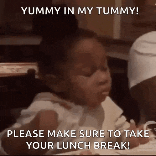 a little girl is sitting at a table with a fork in her mouth eating food .