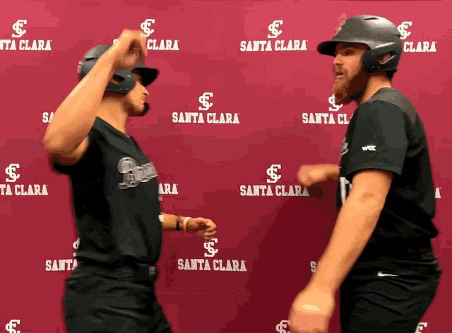 two baseball players stand in front of a santa clara backdrop