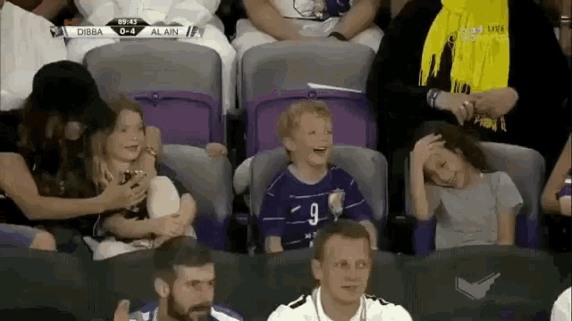 a group of people sitting in a stadium watching a game between dibba and al-ain