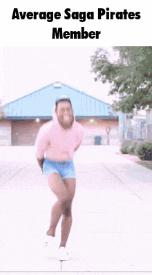 a man in a pink shirt and shorts is dancing on a sidewalk in front of a building .