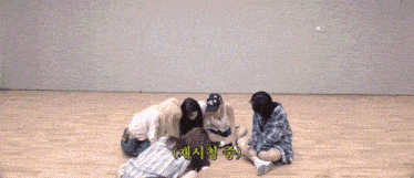 a group of girls are laying on the floor in a room with korean writing on the wall .