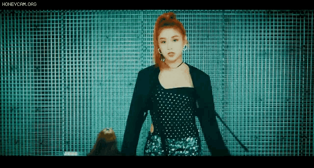 a woman with red hair and a black jacket is standing in front of a grid wall .
