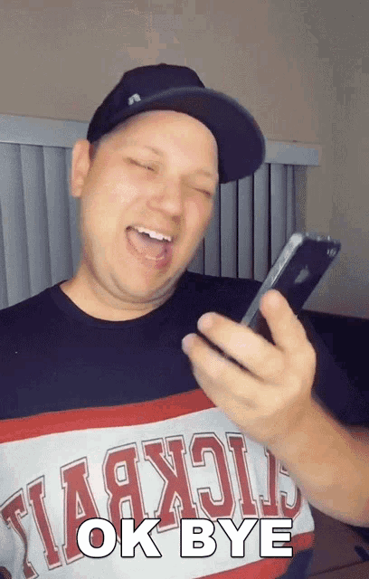 a man wearing a shirt that says ok bye holds a cell phone