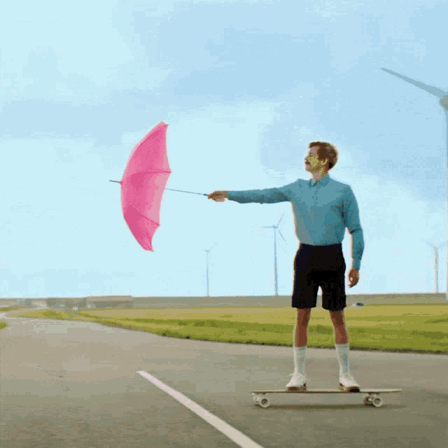 a man on a skateboard holds a pink umbrella
