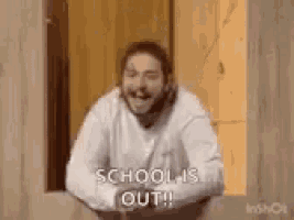 a man with a beard is sitting in front of a window and laughing while saying `` school is out '' .
