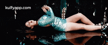 a woman in a sequined dress is laying on her stomach in a pool of water .