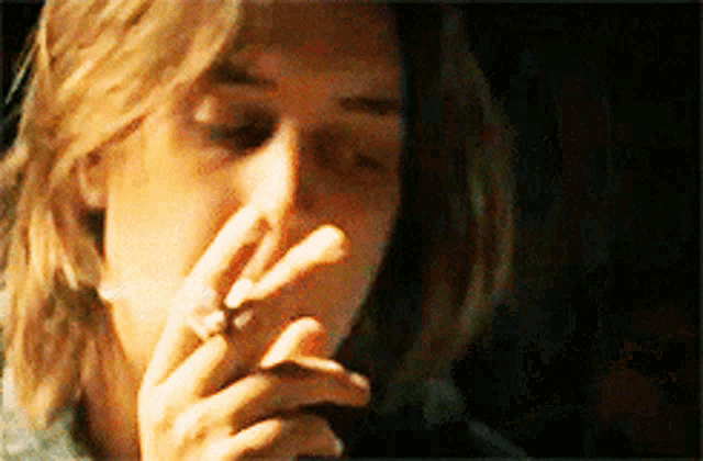a close up of a person smoking a cigarette with a ring on their finger