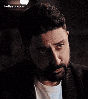 a man with a beard is making a funny face while looking at the camera .
