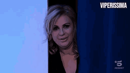 a woman is peeking out from behind a blue curtain in a room .