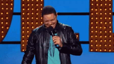 a man in a leather jacket is holding a microphone and smiling on a stage .