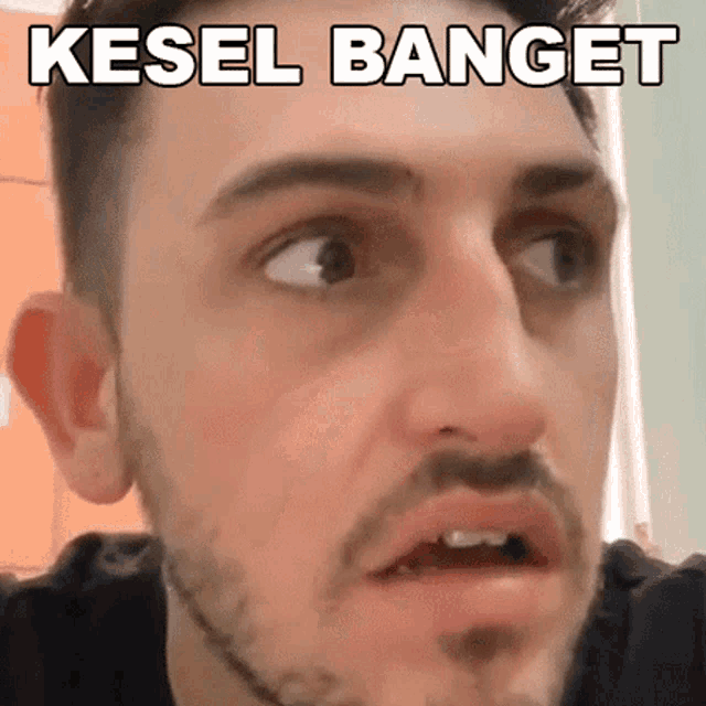 a man with a beard is making a funny face with the words kesel banget written above his face .