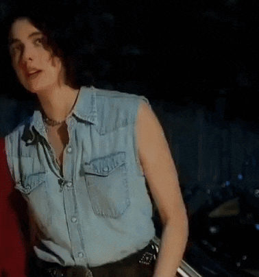 a woman in a denim shirt holds her hand to her hair