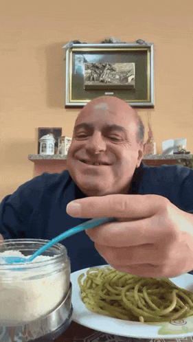 a man is eating spaghetti with a spoon and smiling