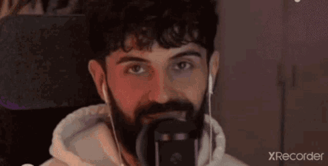 a man with a beard is wearing headphones and looking at the camera with xrecorder in the corner