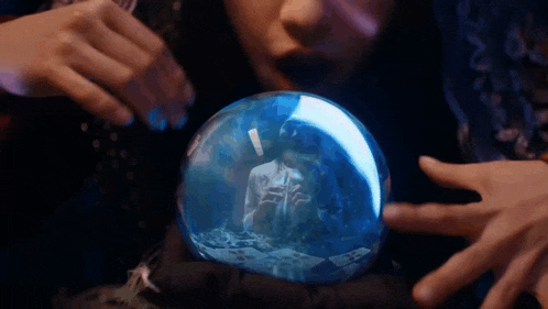 a woman is looking at a snow globe with a reflection of a man in it