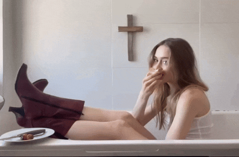 a woman sitting in a bathtub with a cross on the wall
