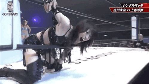 a woman is kneeling down in a wrestling ring with a rope around her neck .