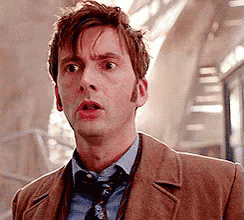 a man wearing a brown jacket and tie is making a surprised face .