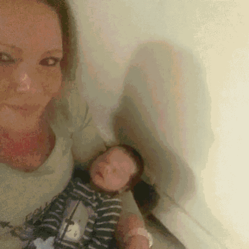 a woman is holding a baby in her arms while the baby is sleeping .
