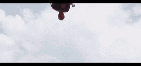 spider-man is holding a captain america shield while jumping in the air .