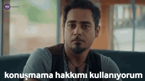 a man with a beard is sitting on a couch with a caption that says konuşmama hakkımı kullaniyorum .