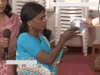 a woman in a blue shirt is holding a piece of paper in her hands