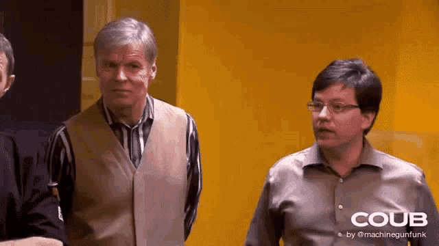 three men are standing in front of a yellow wall with the word coub on the bottom right