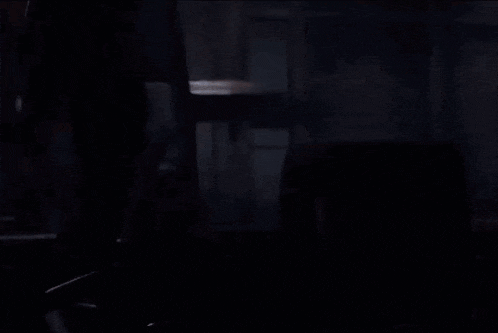 a man in a black shirt is standing in a dark room with his eyes closed