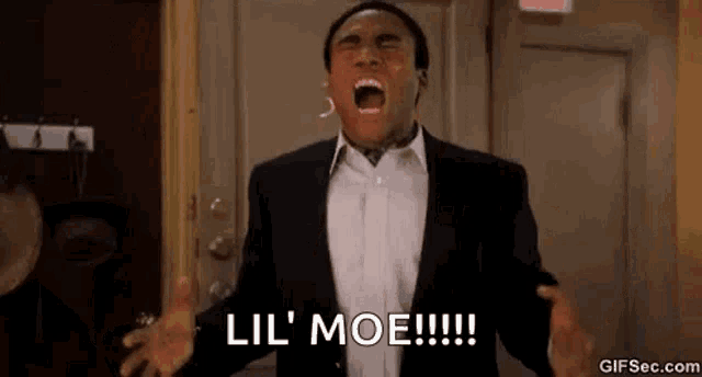 a man in a suit and white shirt is screaming with his mouth open in a room .