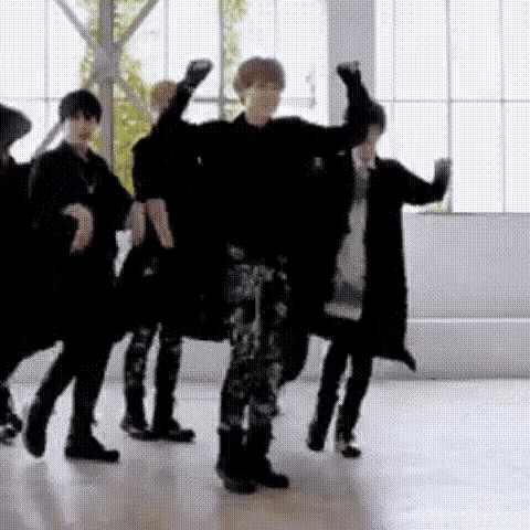 a group of people are dancing in a room with their hands in the air .