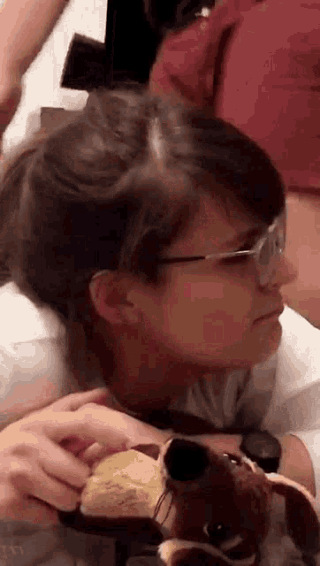 a girl wearing glasses is holding a stuffed animal .
