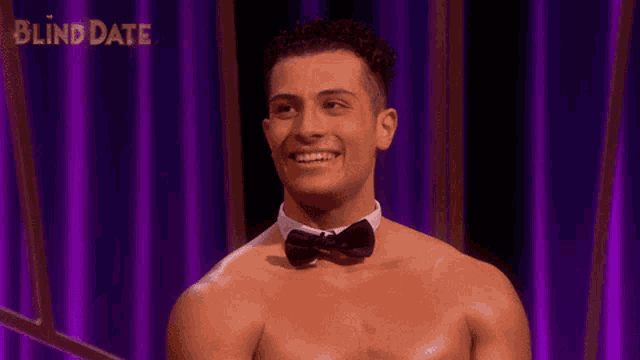 a shirtless man wearing a bow tie is smiling in front of blind date curtain
