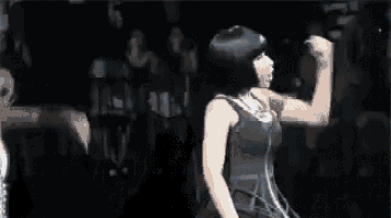 a man is standing on a stage with a microphone in his hand and a woman is standing behind him .