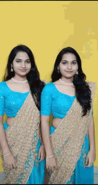 two young women in blue and gold dresses are standing next to each other .
