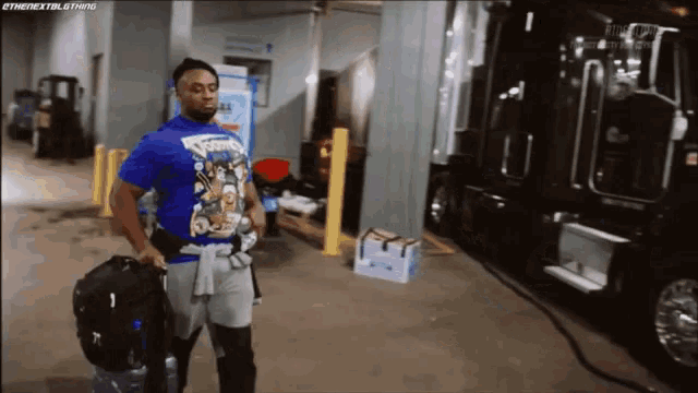 a man in a blue shirt is walking in a warehouse with a suitcase